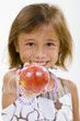 Photo: A young girl holds a red apple. A young girl holds a red apple.