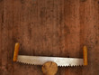 two-handled saw on wooden plank background