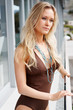 Young female in a monokini standing by a railing of the balcony
