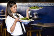Photo: Hispanic waitress in restaurant serving salad plates Hispanic waitress in restaurant serving salad plates