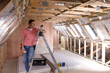 Electrician leaning against ladder in attic under construction