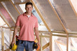Smiling electrician standing in attic under construction