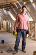 Smiling electrician standing in attic under construction