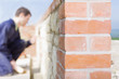 Close up of brick wall with bricklayer in background