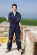 Smiling bricklayer standing next to brick wall