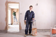 Smiling man mixing plaster in house under construction
