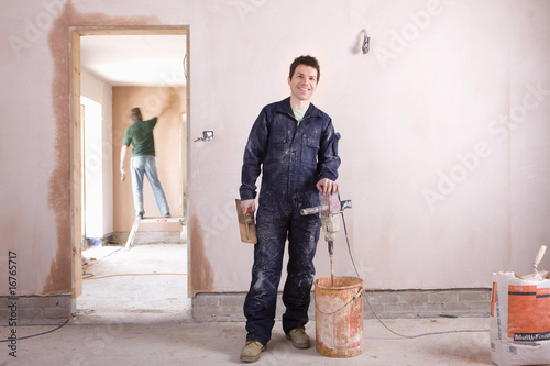 Photo: Smiling man mixing plaster in house under construction Smiling man mixing plaster in house under construction