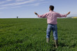 Farmer standing with arms outstretched in young wheat field