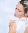 Beautiful young woman standing under streams of water