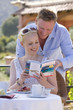 Photo: Couple looking at travel guidebook on cafe patio Couple looking at travel guidebook on cafe patio
