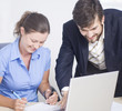 Business couple working on a laptop and sign document