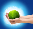 Human hands holding green planet