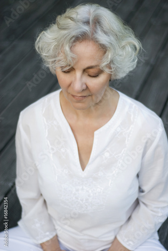 Photo: Seniorin meditiert auf der Sonnenterrasse Seniorin meditiert auf der Sonnenterrasse