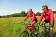 Sportive couple riding mountain bike in meadow