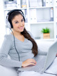 Young woman sitting on couch and working on laptop