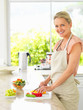 Happy woman preparing salad in the kitchen