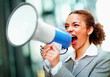 Frustrated young business woman yelling into a bullhorn