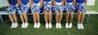 Group of cheerleaders sitting in row on bench, low section