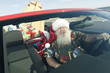 Father Christmas sits in red convertible with surfboard
