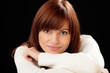 Woman on black background resting her head on hands