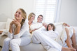Family sitting together on white sofa watching television