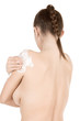 Beautiful young female applies moisturizer on back