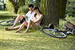 A young couple sitting under a tree using a mobile phone