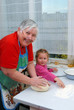 Grandmother and granddaughter knead the dough