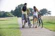 A young couple pushing bicycles uphill