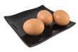 three fresh eggs on black plate isolated on white background