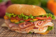 Turkey & ham sub with fresh vegetables in the background