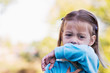 Photo: Little girl coughing or sneezing into her elbow. Little girl coughing or sneezing into her elbow.