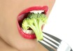 Broccoli on steel fork in woman mouth Broccoli on steel fork in woman mouth