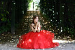Beautiful woman in a red dress walking in alleyway in park