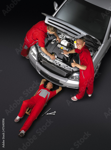 Motor mechanics are working around the car-red
