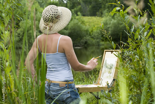 Photo: Young woman painting landscape in the open air Young woman painting landscape in the open air