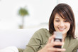 Cute young female reading an SMS on  mobile