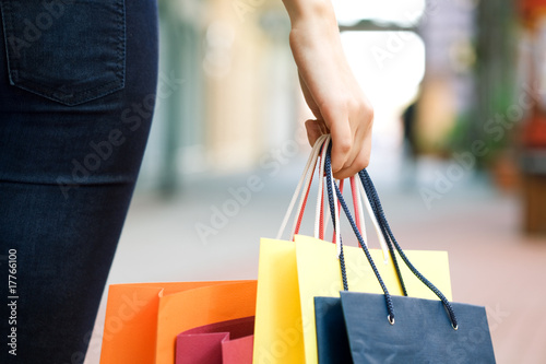 Photo: hand of young woman with multi-coloured bags hand of young woman with multi-coloured bags