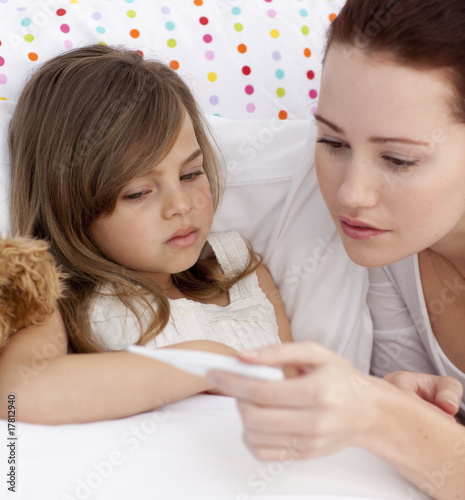 Photo: Portrait of mother taking her daughter's temperature Portrait of mother taking her daughter's temperature