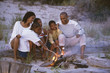 African family roasting marshmallows on beach