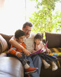 Grandfather reading to grandchildren on sofa