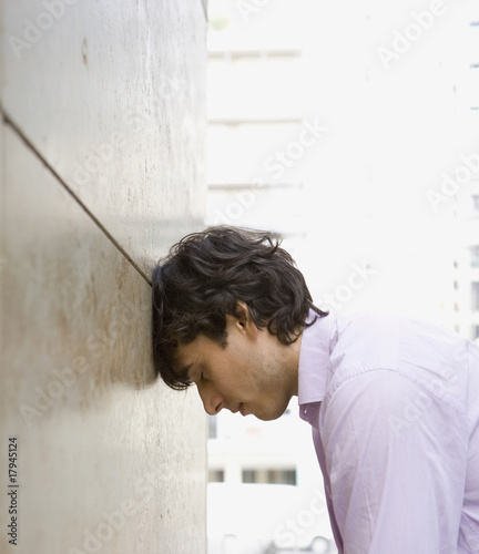 Foto: Businessman leaning head against wall Businessman leaning head against wall