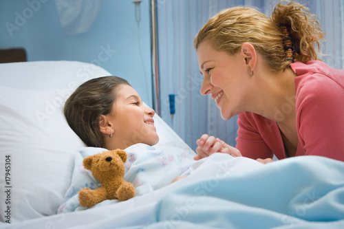 Photo: Mother smiling at daughter in hospital bed Mother smiling at daughter in hospital bed