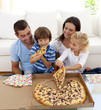 Young family eating pizza in living-room