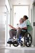 Elderly man sitting on the wheelchair assisted by his wife