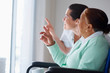 Elderly woman on a wheelchair , nurse pointing outside