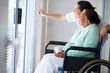 Old woman on a wheelchair , nurse pointing outside