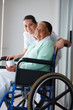 Happy retired woman on the wheel chair with a nurse