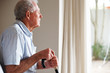 Old man holding a walking stick looking outside Old man holding a walking stick looking outside