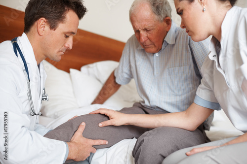 Photo: Elderly man with a knee injury being checked by doctors Elderly man with a knee injury being checked by doctors
